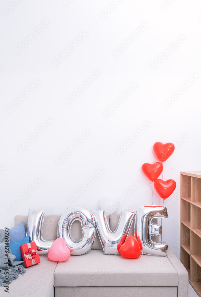 Foil love balloons and gifts on a sofa with white wall in background for Valentines day, Mothers d