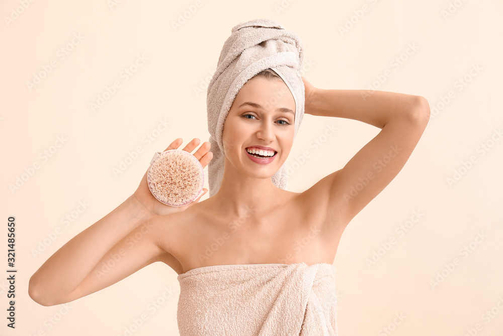 Beautiful young woman with massage brush on light background