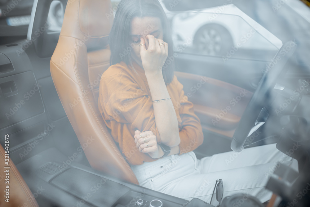 Young woman feeling stressed, having a headache while sitting on the drivers seat of the convertibl