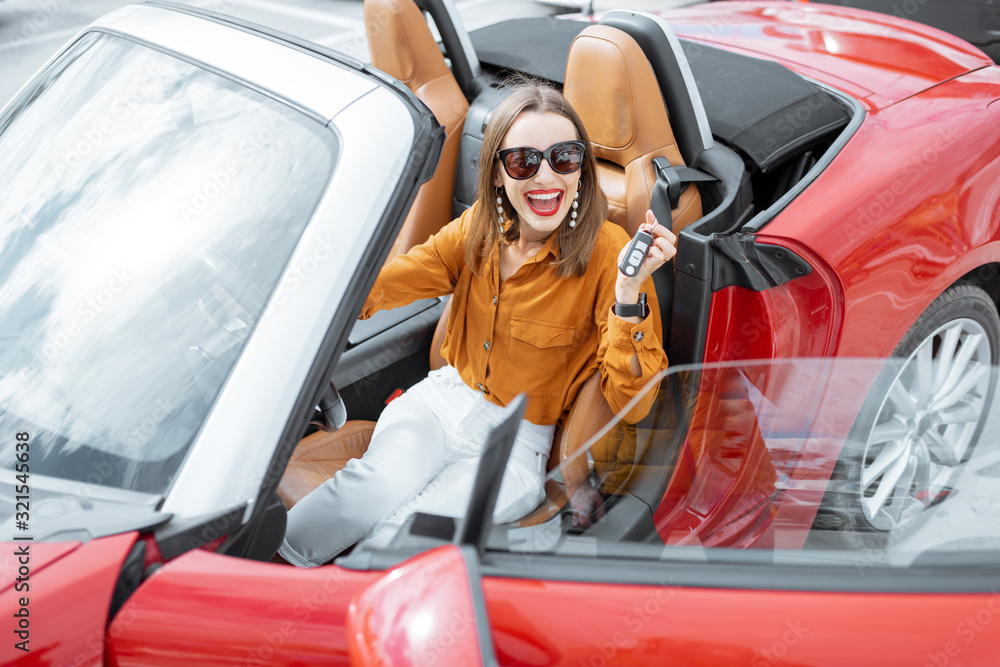 Portrait of cheerful woman feeling happy while sitting in the new sports car. Concept of a happy car