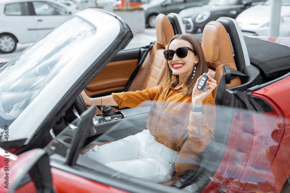 Portrait of cheerful woman feeling happy while sitting in the new sports car. Concept of a happy car