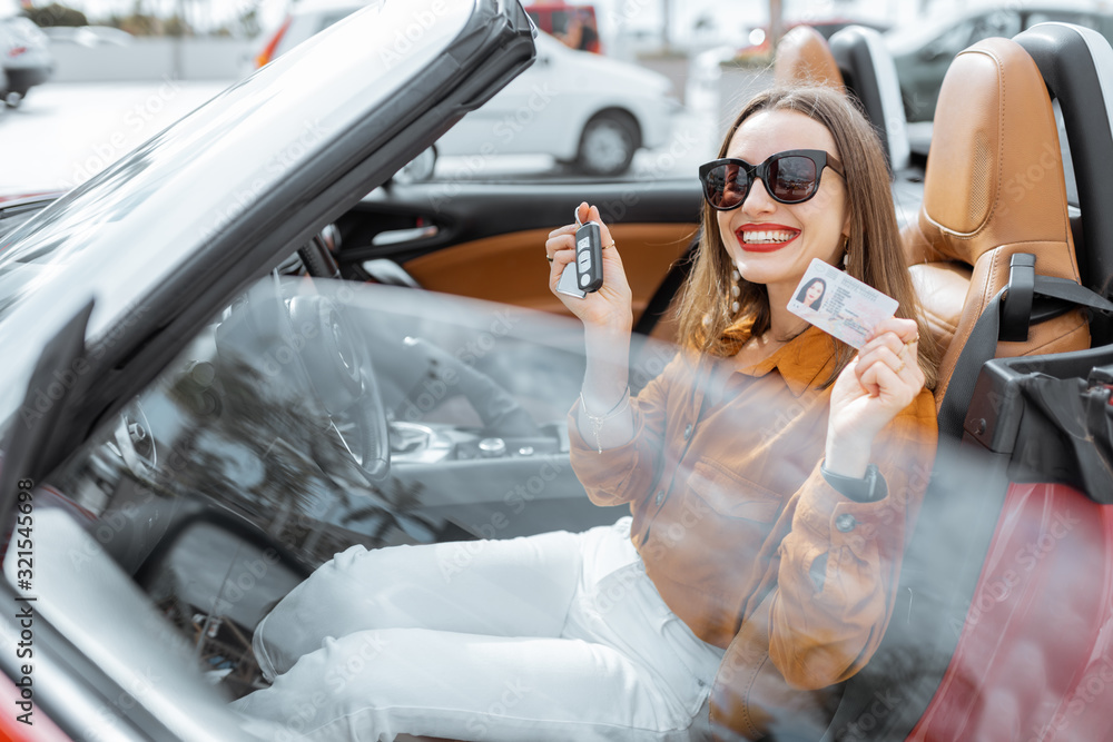 Portrait of cheerful woman feeling happy while sitting in the new sports car. Concept of a happy car