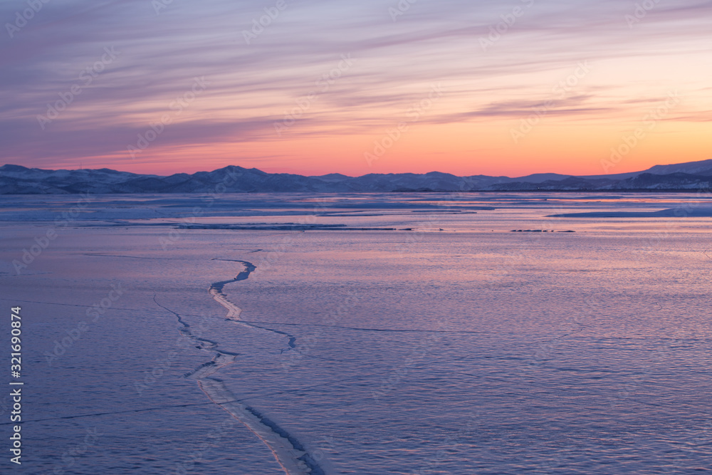 Ice details of the frozen lake Baikal during a winter sunrise. Irkutsk, Siberia, Russia.