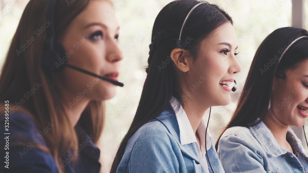 Customer support agent or call center with headset works on desktop computer while supporting the cu