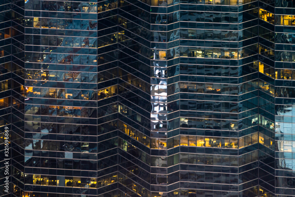 Skyscraper exterior of office building with lights turn on at some windows.