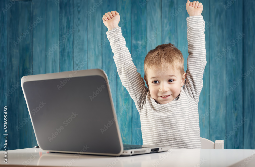 happy five years old child sitting with a laptop at table