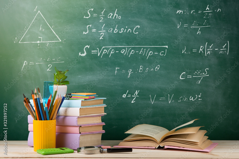 Education and reading concept - group of colorful books on the wooden table in the classroom, blackb