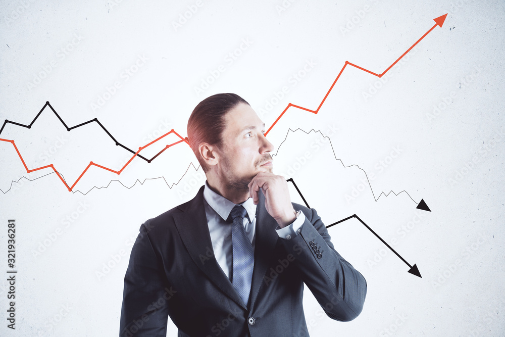 Thinking businessman in suit standing near gray wall with drawing arrows