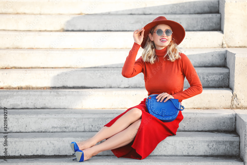 Portrait of fashionable young woman sitting on steps outdoors