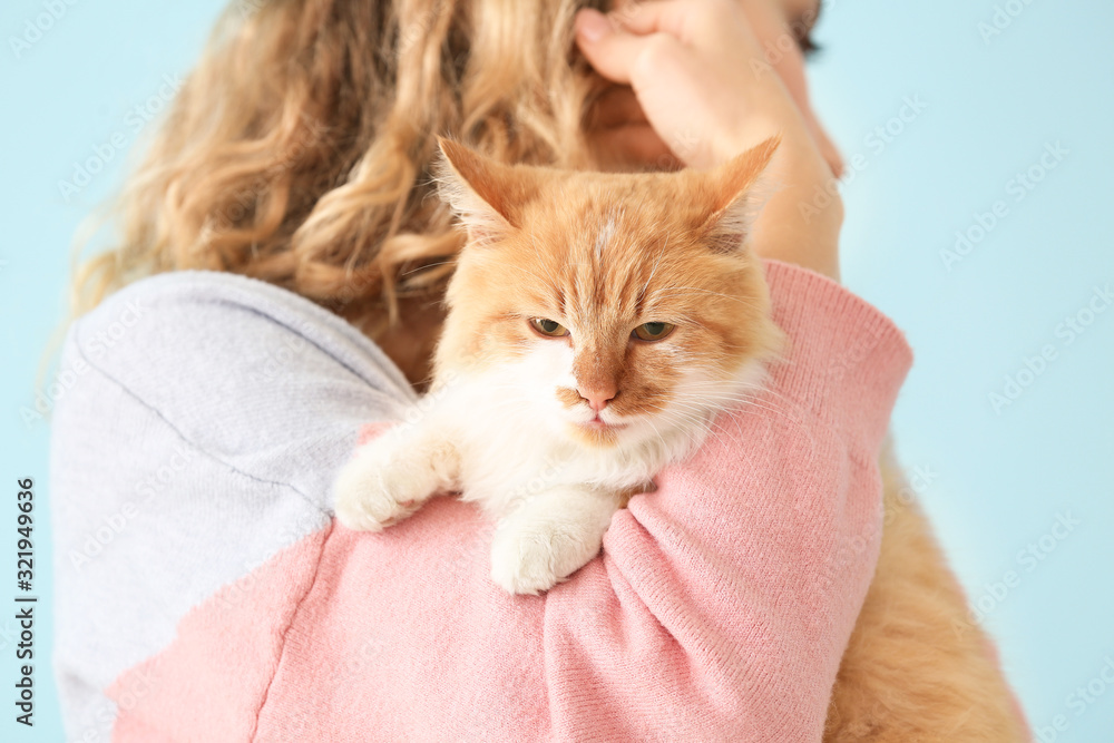 Beautiful young woman with cute cat on color background