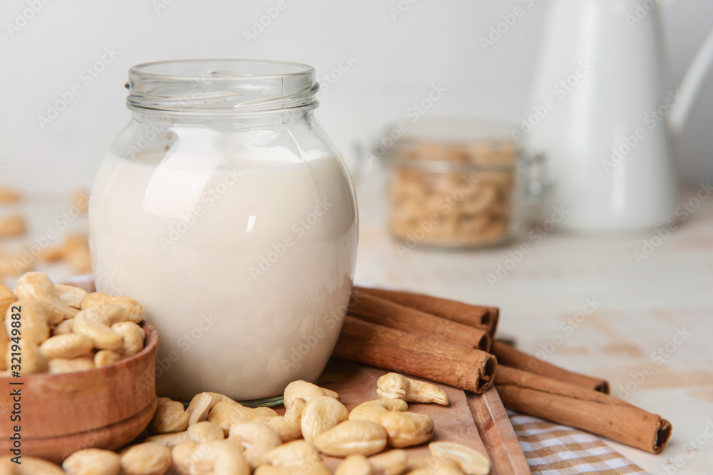 Jar of cashew milk with nuts on wooden table