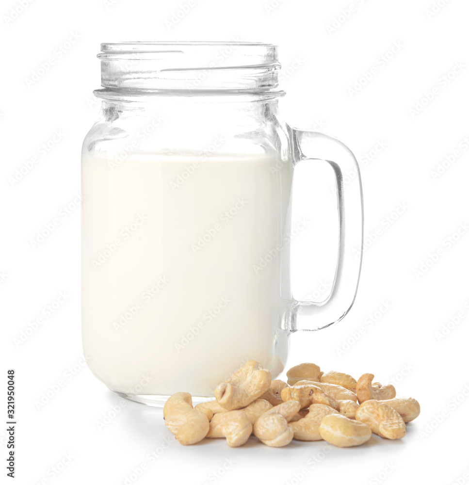 Jar of cashew milk with nuts on white background