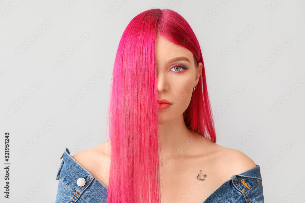 Beautiful young woman with unusual hair color on light background