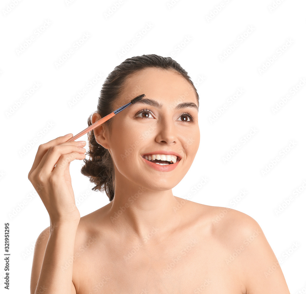 Beautiful young woman applying makeup on white background