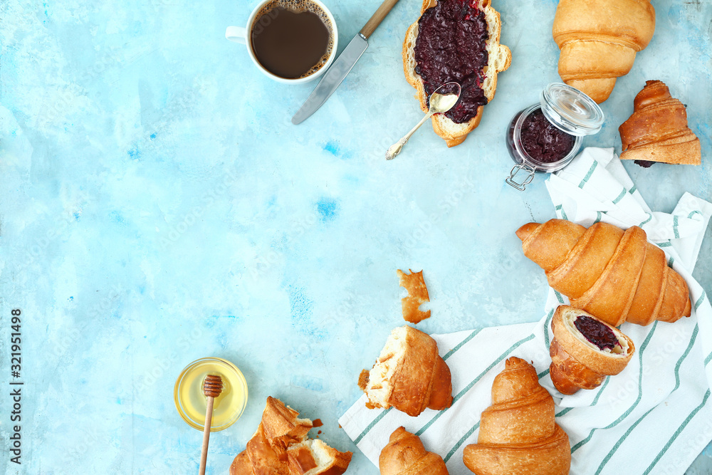 Tasty sweet croissants with jam, honey and coffee on color background