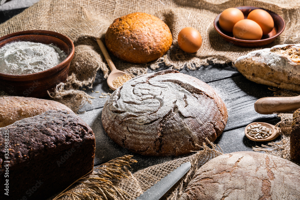 Different fresh bread and wheat on the wooden