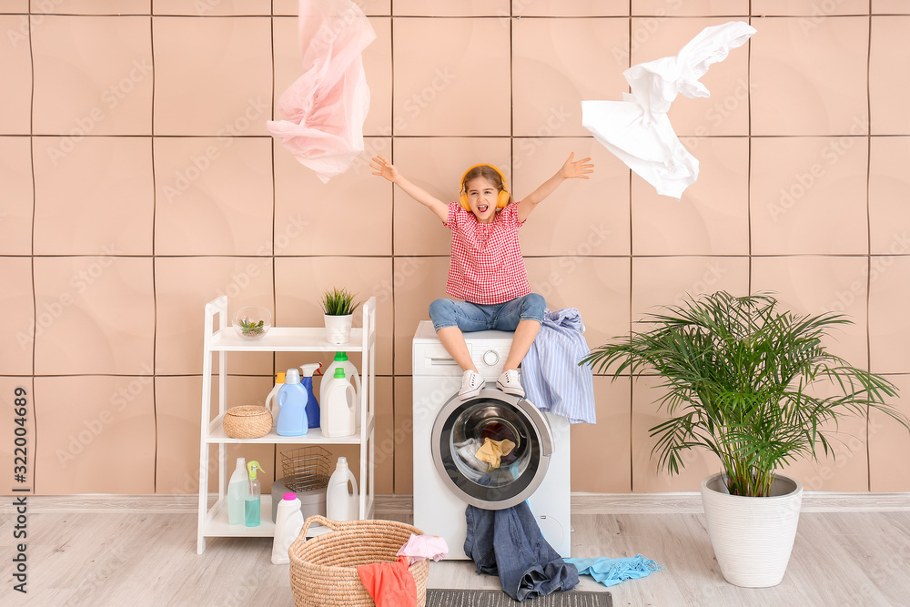 Little housewife listening to music in laundry room