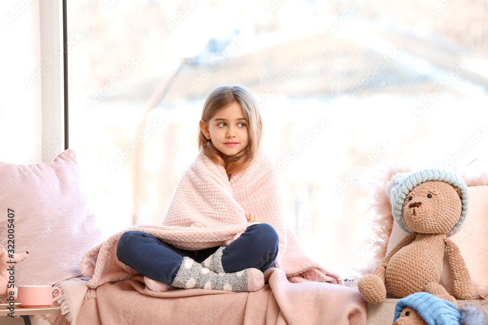 Cute little girl on window sill at home