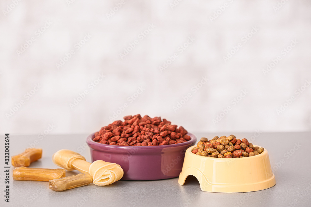 Bowls with dry pet food on table