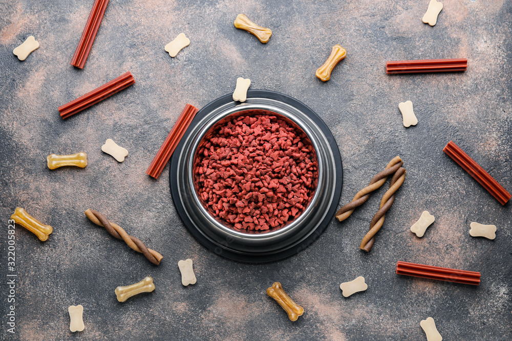 Bowl with dry pet food on grey background