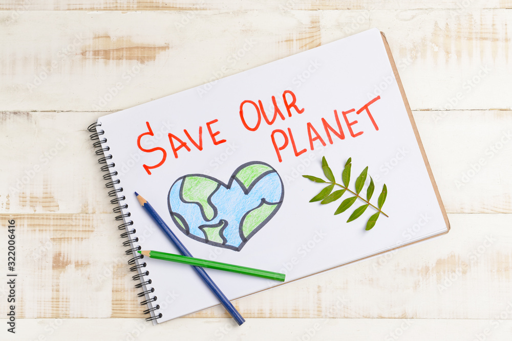 Notebook with drawing and text SAVE OUR PLANET on wooden background. Earth Day celebration