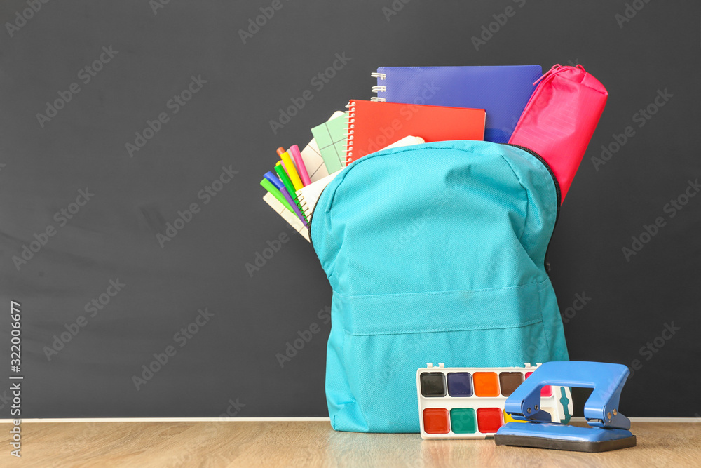 School backpack with stationery on table in classroom