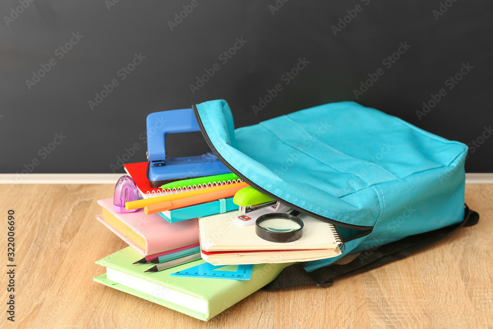 School backpack with stationery on table in classroom