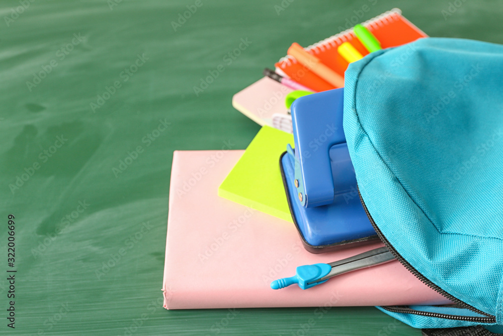 School backpack with stationery on color background