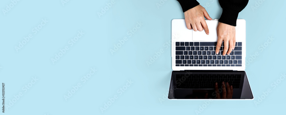 Person using a laptop computer on a solid color background