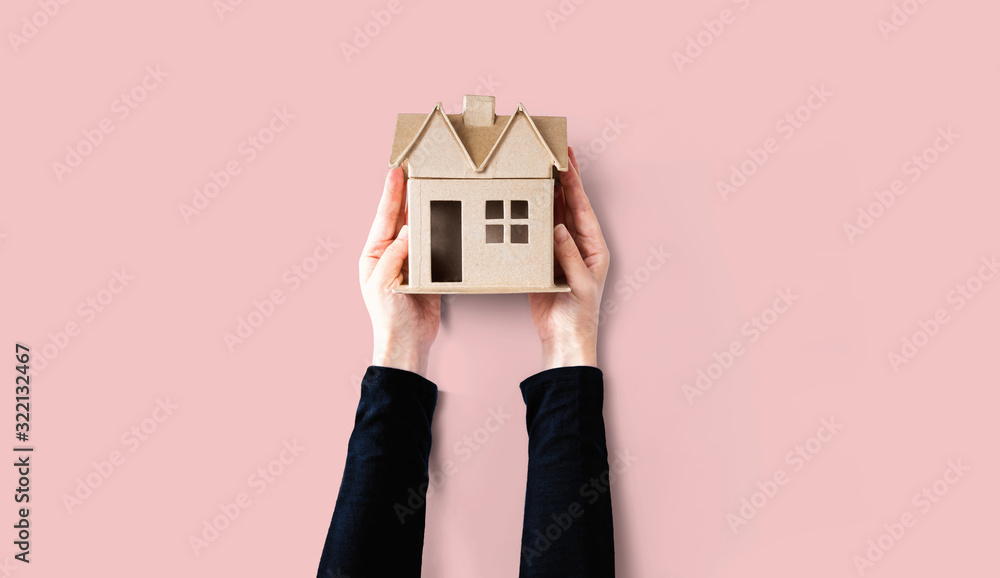 Woman holding a cardboard house overhead view