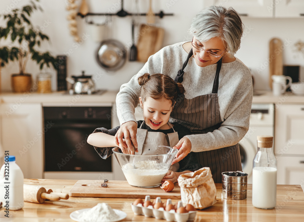 happy family grandmother and granddaughter child cook in the kitchen, knead dough, bake cookies