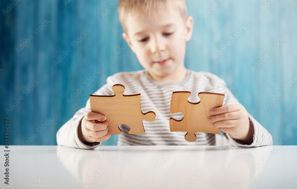 Little child holding puzzle pieces and trying to solve it