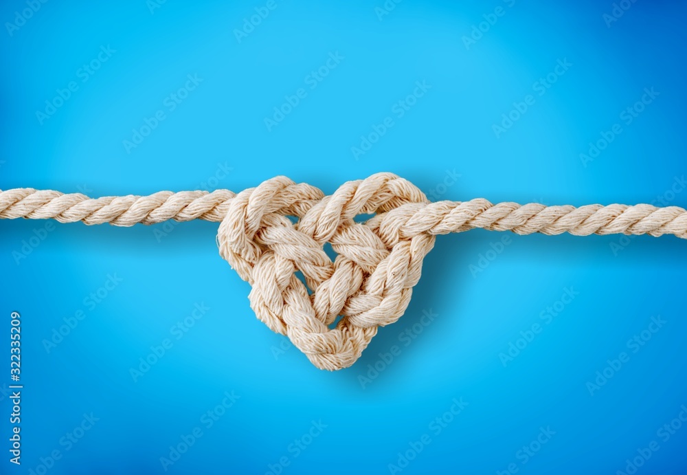 White rope in heart shape knot on background. Love concept.