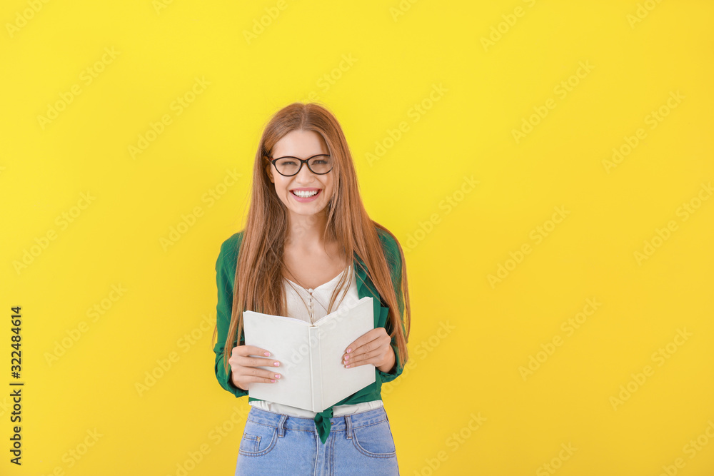 Beautiful young woman with book on color background