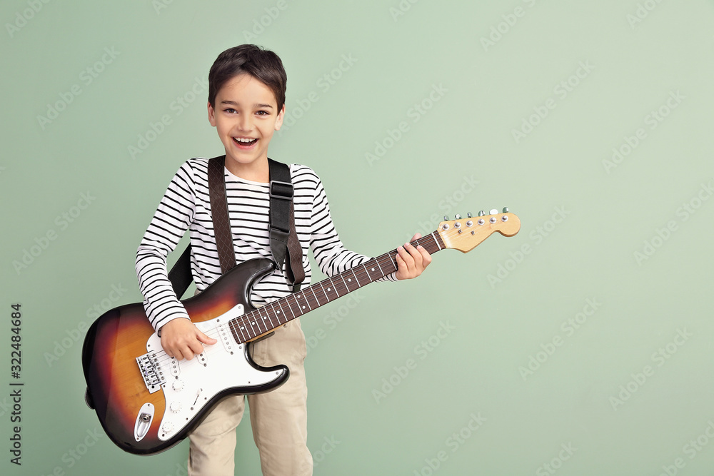 Little boy playing guitar on color background