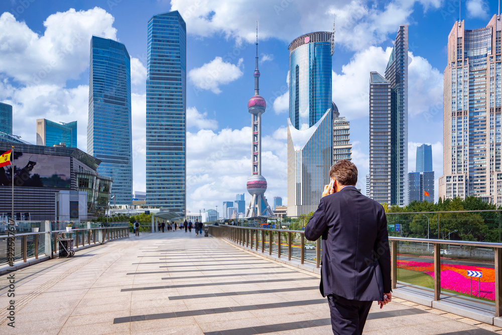 Business man walking and use smartphone in shanghai city