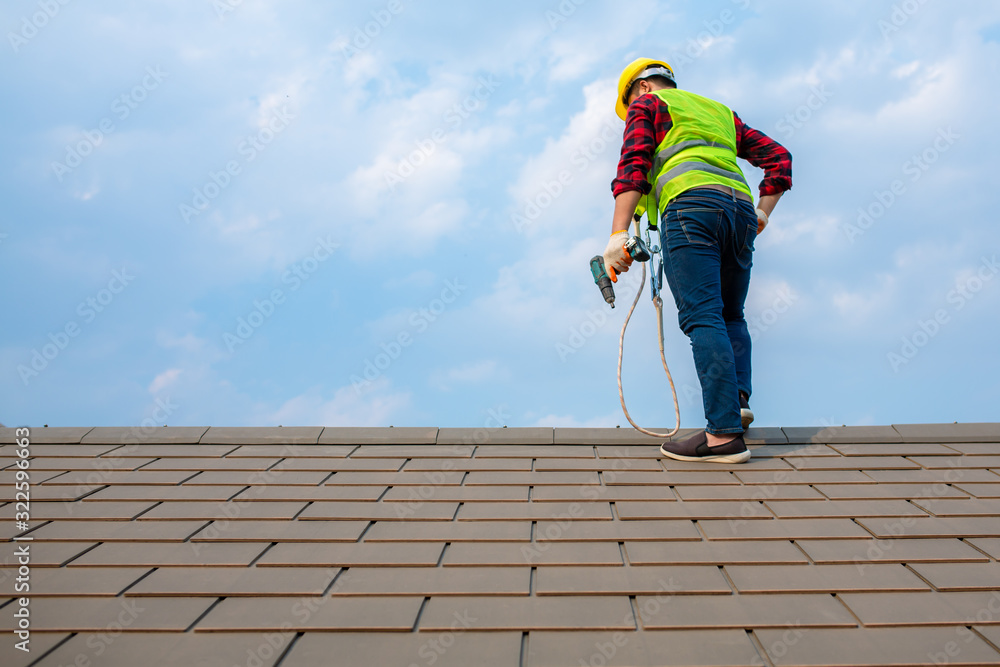 Construction workers Fixing roof tiles, with roofing tools, electric drills used on roofs in safety 