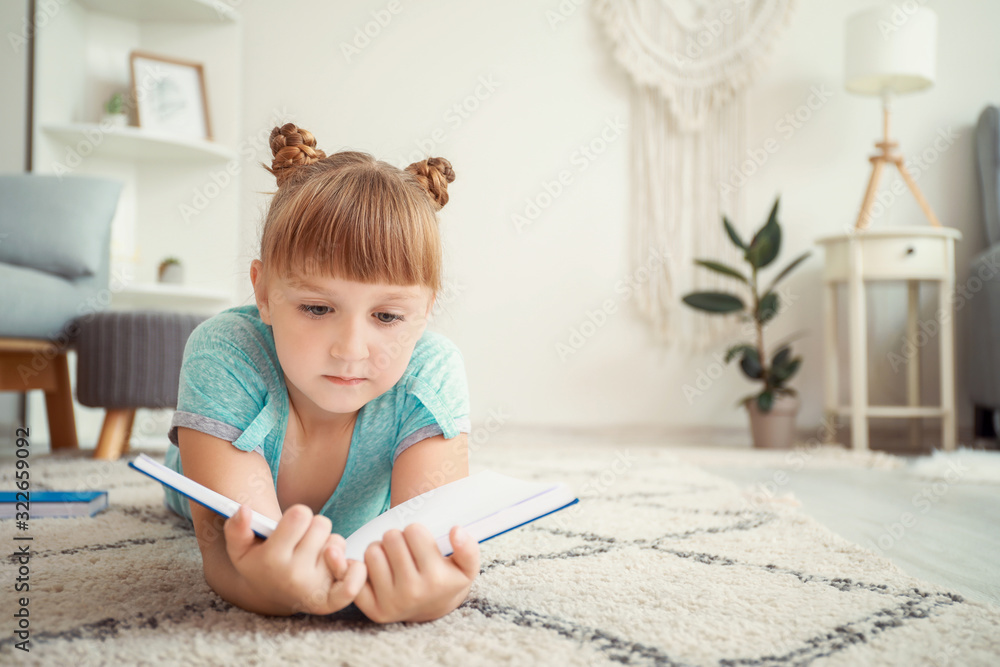 Cute little girl reading book at home