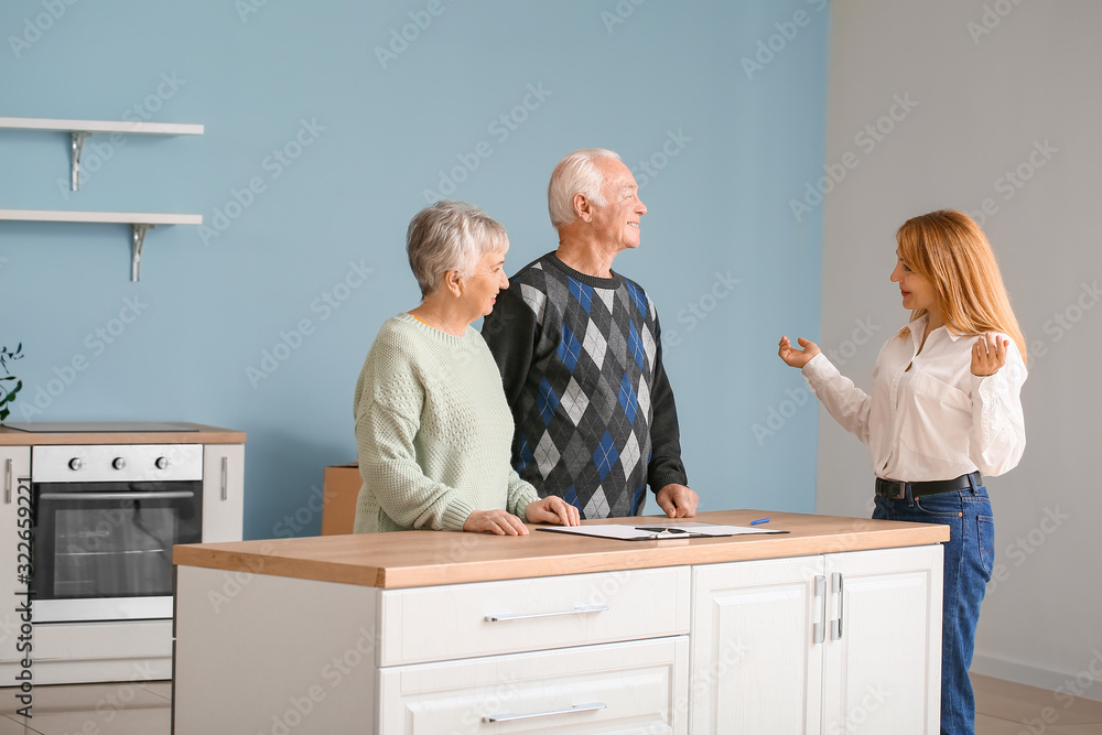 Female real estate agent working with senior couple indoors