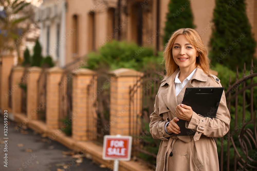 Female real estate agent near house for sale outdoors