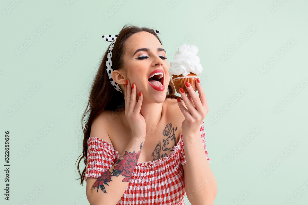 Beautiful housewife with cupcake on color background