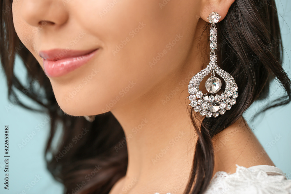 Young bride with beautiful jewelry on color background, closeup