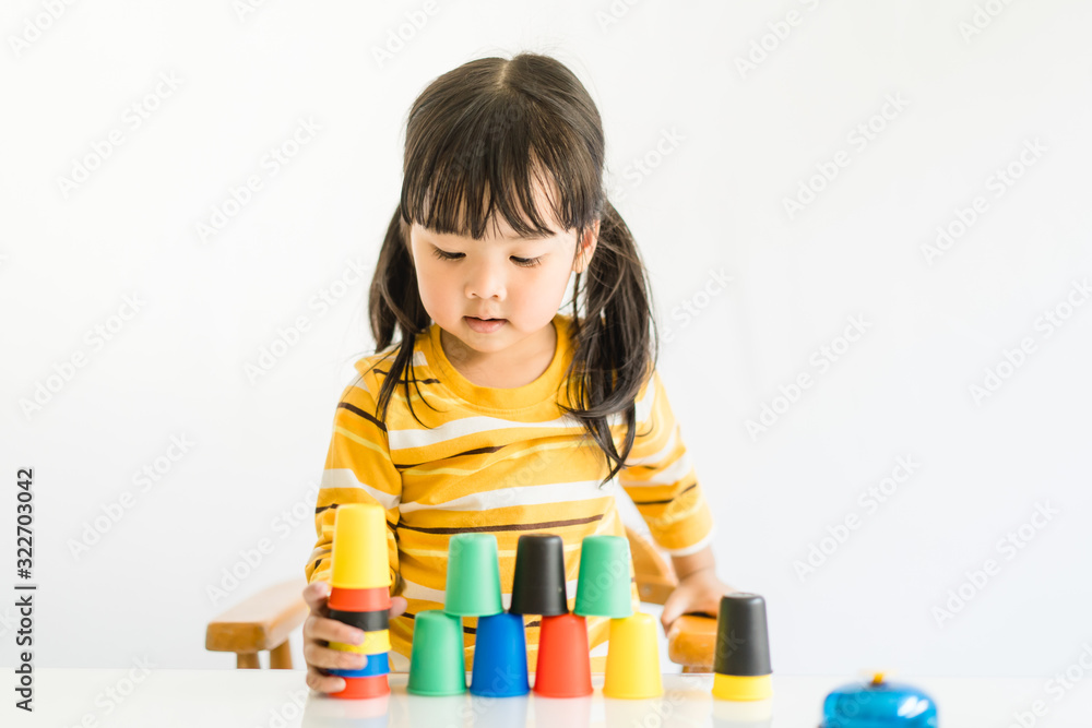 Little asian toddler girl playing stacking cups learning materials in a montessori methodology schoo