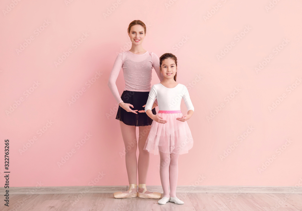 Little ballerina training with coach against color background