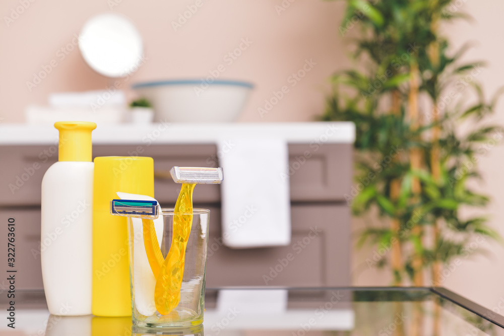 Razors for hair removal with cosmetics on table in bathroom