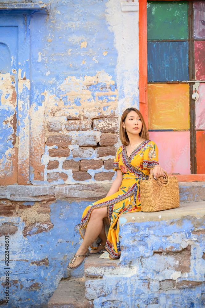 Portrait of young woman in front colorful blue tone building in Jodhpur the blue city in Rajasthan I