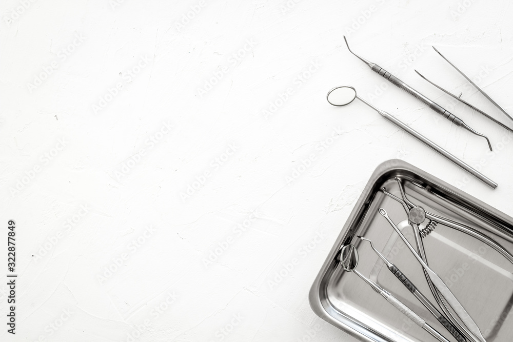 Stomatological tools in tray on dentists desk on white background top-down frame copy space