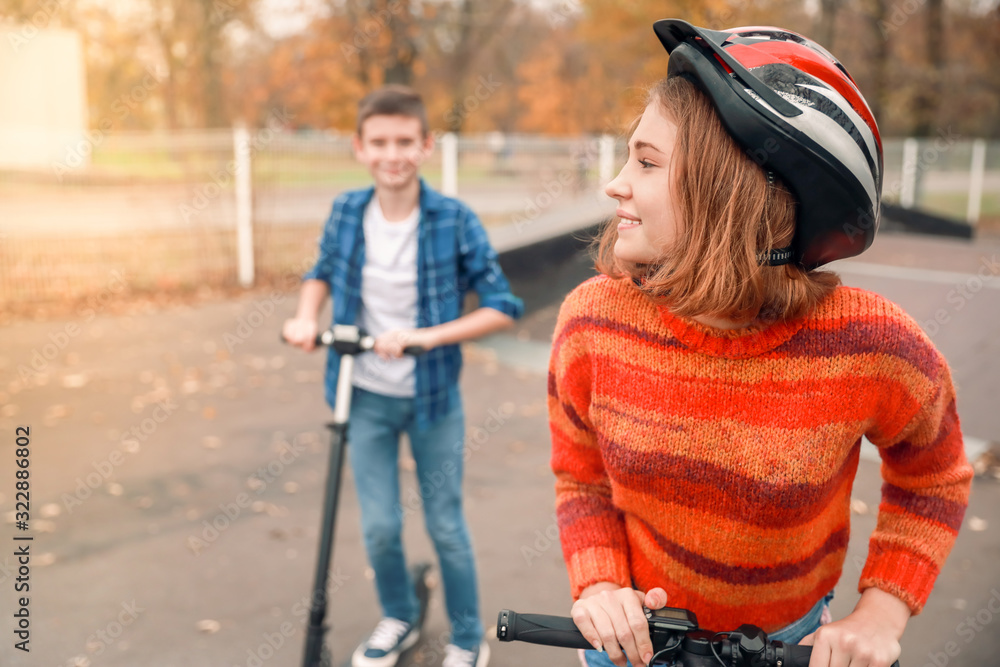 Active teenagers riding kick scooters in skate park