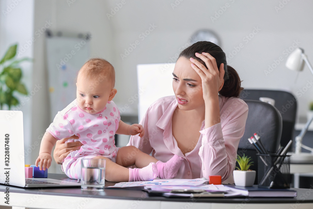 Stressed mother with her baby working in office