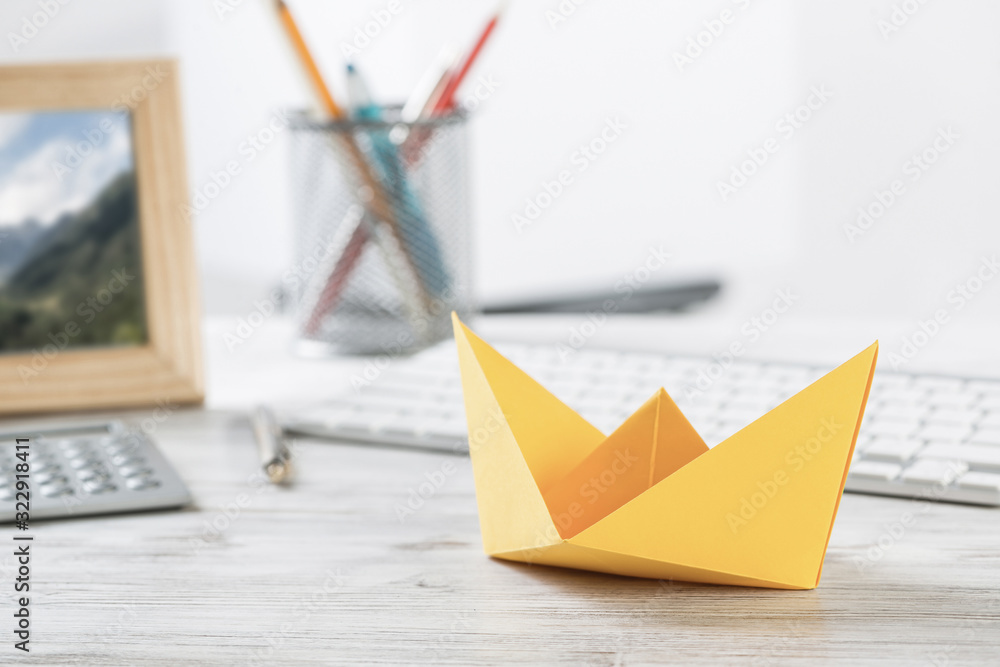 Businessman desk with yellow paper ship